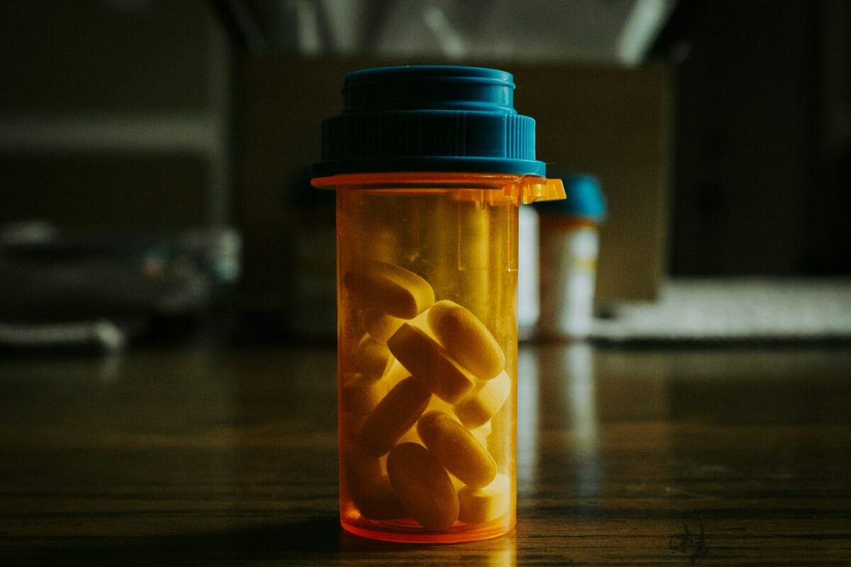 Amber prescription bottle filled with tablets on a wooden table